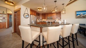 A modern kitchen with a central island, bar stools, stainless steel appliances, and pendant lighting. - Hot Tub | Winter Getaway & Mountain Views (Fraser)