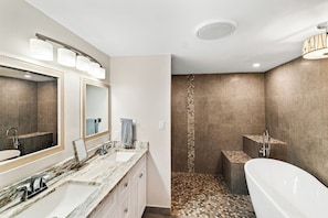 A modern bathroom with a large mirror, two sinks, a bathtub, and a shower area. - Compass 2BR Suite - Gourmet Kitchen - Water view (Cocoa Beach)