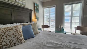 A hotel room with a bed, two nightstands, a lamp, a clock, and a window with blinds.