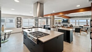 A modern kitchen with a central island, built-in appliances, and a large window providing a view. - Compass 2BR Suite - Gourmet Kitchen - Water view (Cocoa Beach)