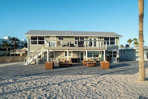 Une propriété située en bord de mer, comprenant un bâtiment à deux étages, un espace extérieur aménagé pour s’asseoir et un escalier menant à un balcon.