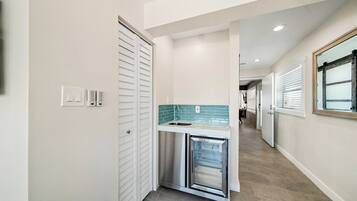 A hallway with a built-in kitchen area featuring a stainless steel refrigerator and a tiled backsplash.