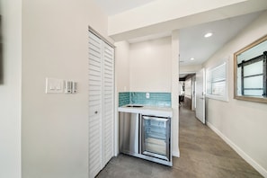 A hallway with a built-in kitchen area featuring a stainless steel refrigerator and a tiled backsplash. - Compass 2BR Suite - Gourmet Kitchen - Water view (Cocoa Beach)