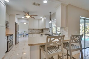 A modern kitchen with white cabinetry, a central island, and a ceiling fan.