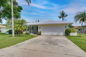 A residential house with a garage, a driveway, and a lawn. - Cape Coral Getaway I Private Saltwater Pool I Family & Dog Friendly (Cape Coral)