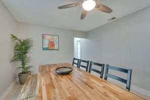 A dining area with a wooden table, chairs, a ceiling fan, a potted plant, and a painting on the wall. - Cape Coral Getaway I Private Saltwater Pool I Family & Dog Friendly (Cape Coral)