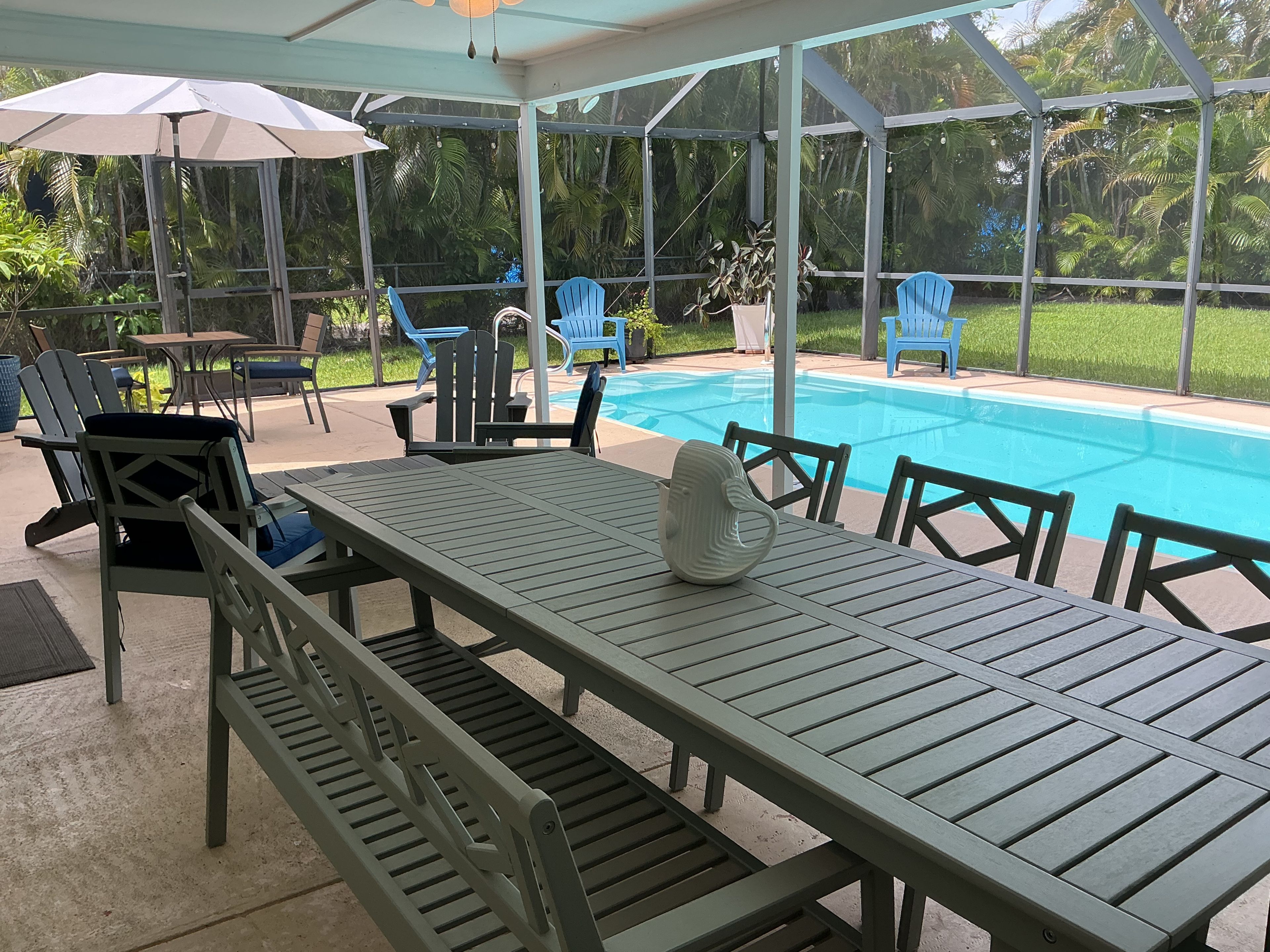 Un espacio al aire libre techado con piscina, asientos y una mesa.