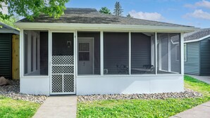 A covered porch with a screened enclosure, a door, and a small seating area.