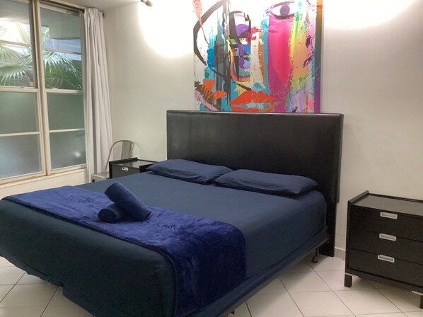 A bedroom with a bed, a nightstand, a dresser, and a window with curtains. - Location, Location, Location!!! OCEAN DRIVE, SOUTH BEACH (Miami Beach)