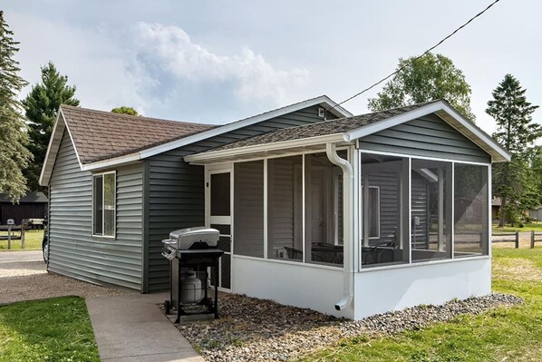 A single-story house with a covered porch, a grill, and a screened-in area.