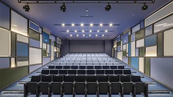 Ein Theater mit Sitzreihen, einer Bühne und einer Decke mit Beleuchtung.