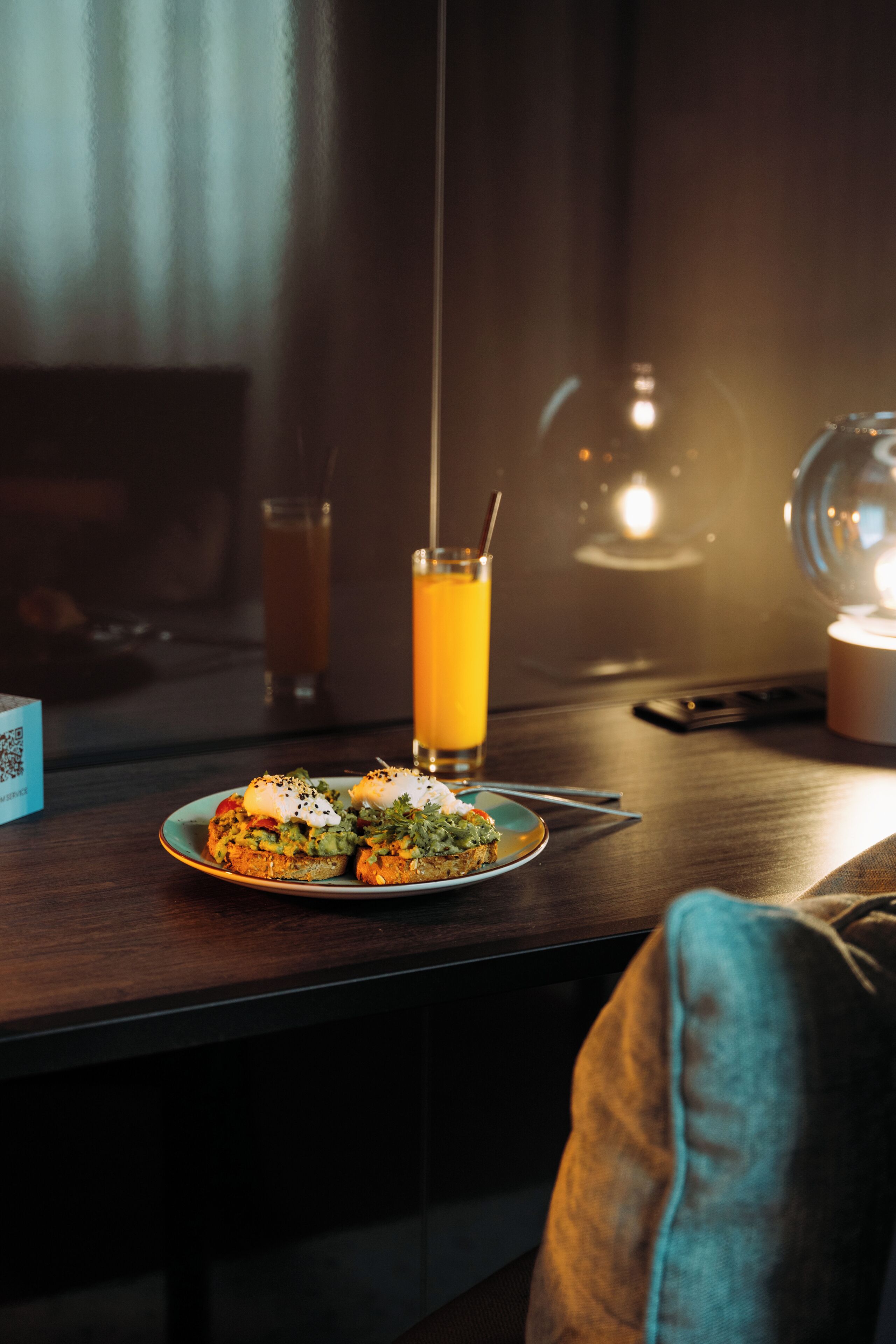 A dining table with a plate of food and a glass of orange juice.