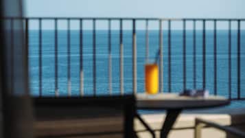 A balcony with a view of the sea, a table with a candle, and a chair.