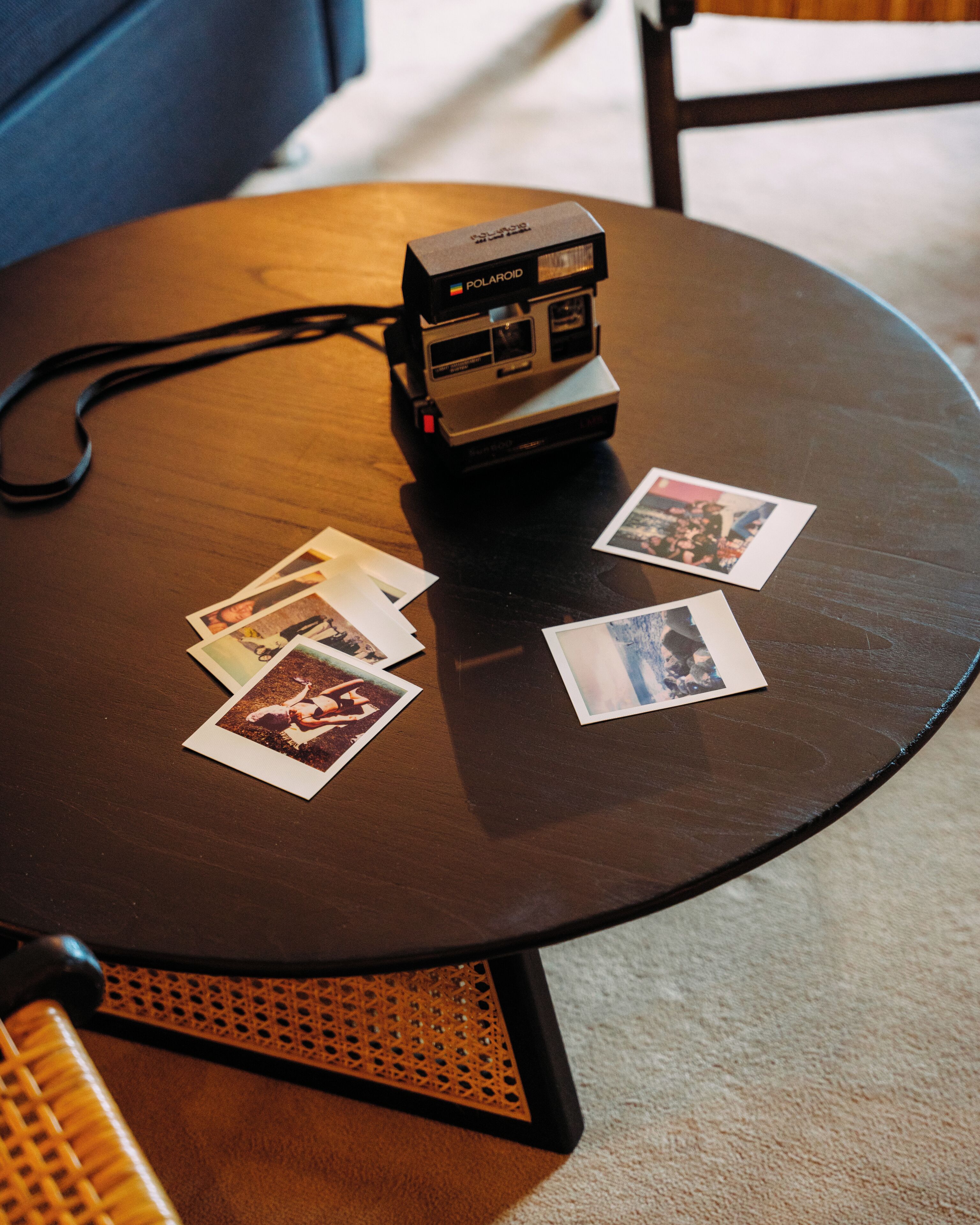 A Polaroid camera on a round table with several Polaroid photos.