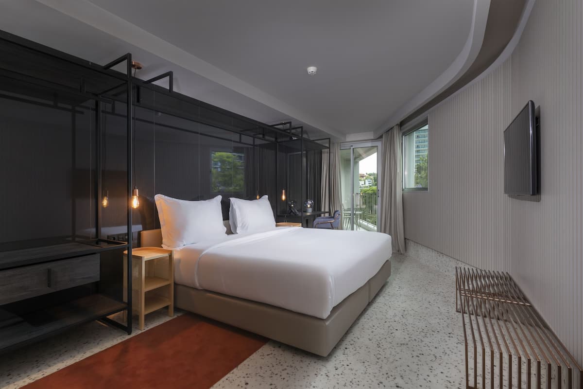 Una habitación de hotel moderna con una cama grande, un escritorio y una televisión.
