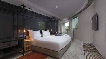 A modern hotel room with a large bed, a desk, and a TV.