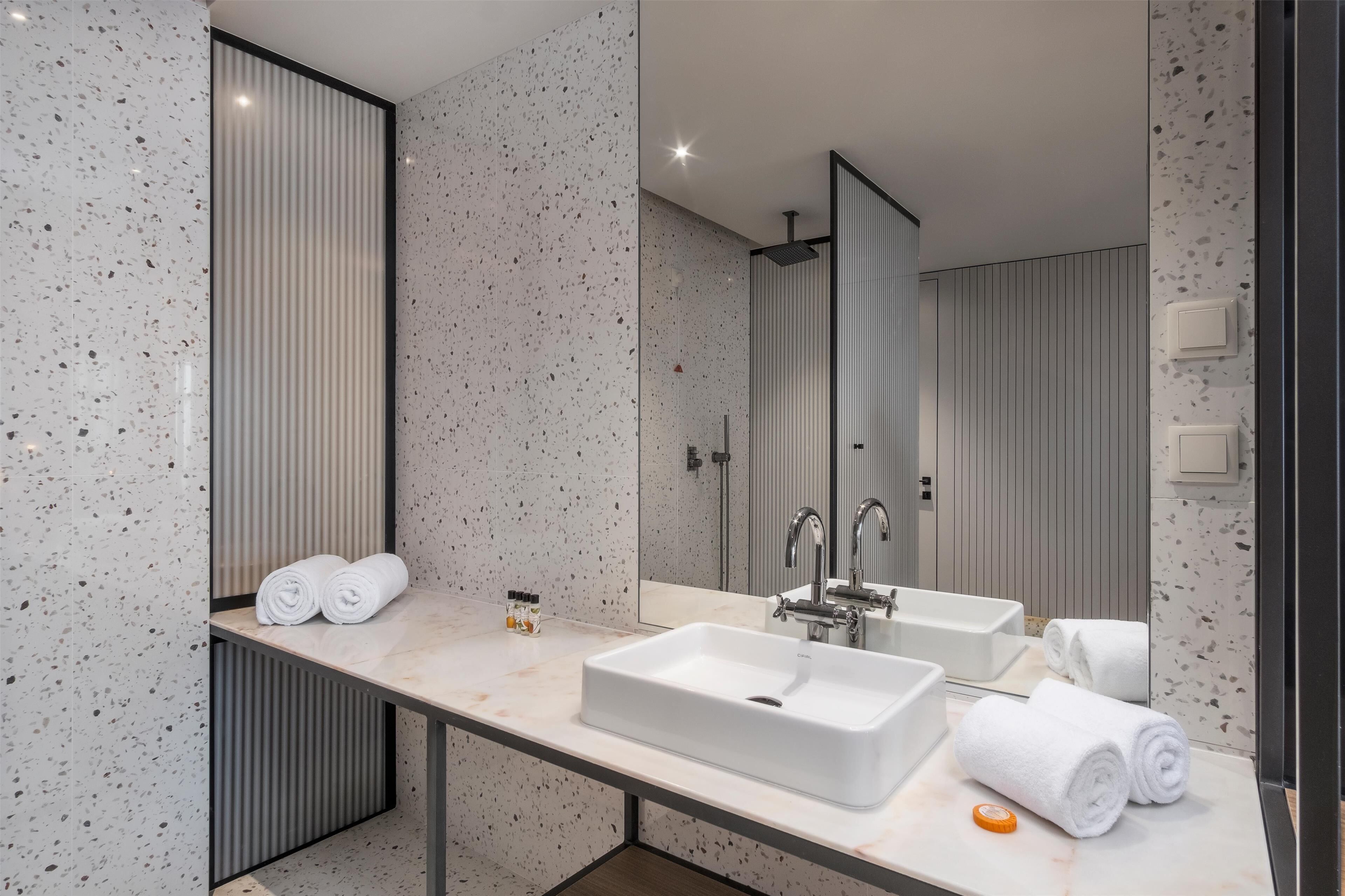 Une salle de bain moderne avec un grand miroir, deux lavabos et un espace douche.