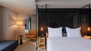A modern hotel room with a large bed, a desk, a chair, a lamp, and a mirror.