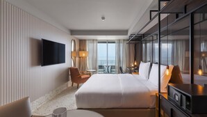 Una habitación de hotel moderna con una cama grande, un televisor de pantalla plana, un escritorio y un balcón con vistas.