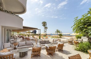 Un salón en la azotea con asientos exteriores, una piscina y vista al océano.