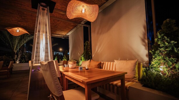An outdoor dining area with a wooden table and chairs, a hanging light fixture, and a potted plant. - NEXT - Savoy Signature (Funchal)