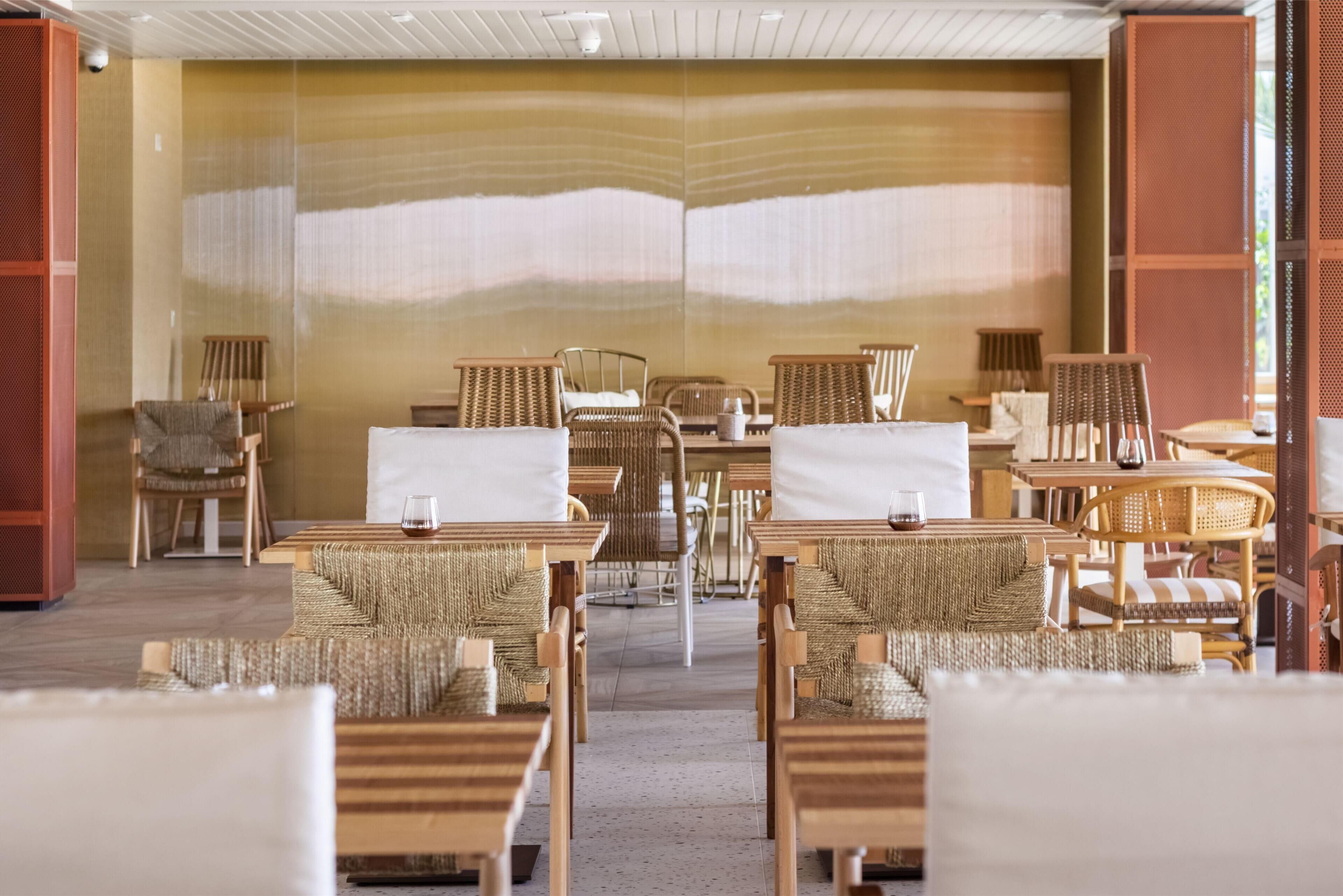 A hotel lobby with a central seating area featuring wicker furniture and a large wall with a textured design.