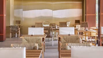 A hotel lobby with a central seating area featuring wicker furniture and a large wall with a textured design.