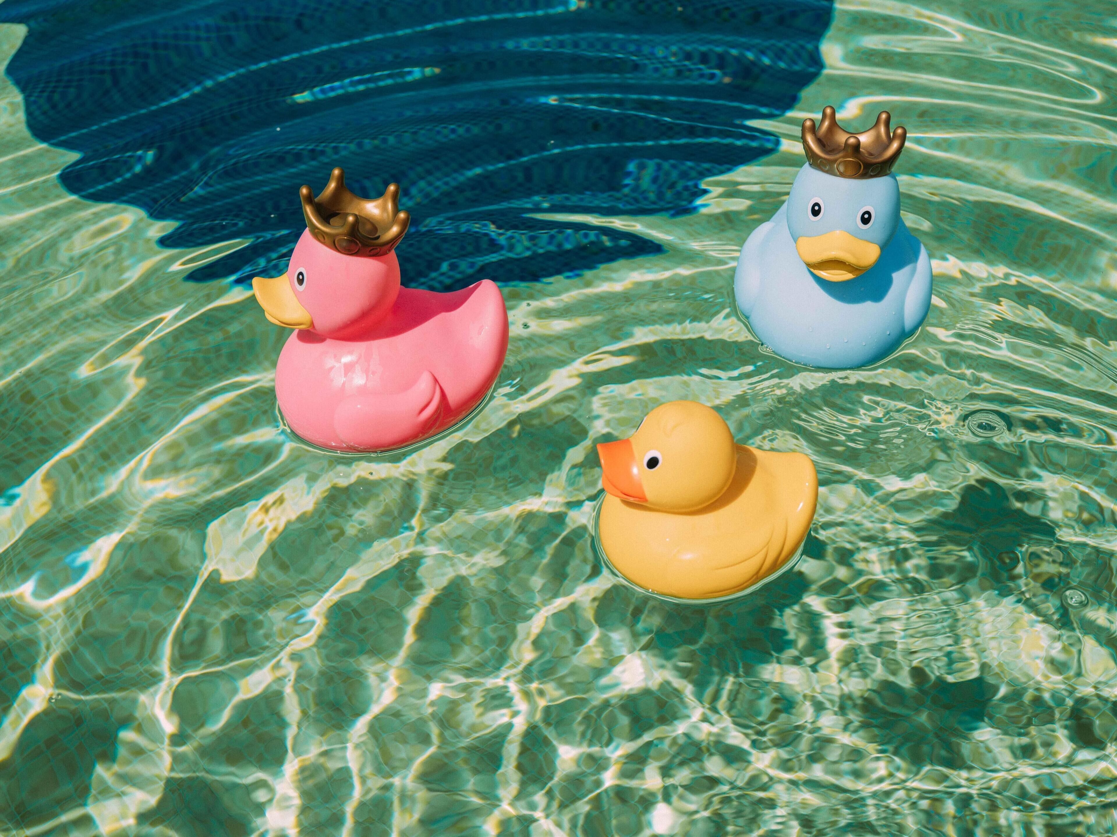 Three rubber ducks floating in clear water.
