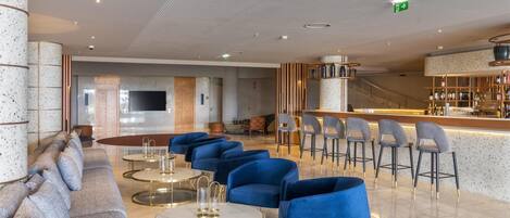 Un vestíbulo moderno con área de bar, asientos y una escalera.