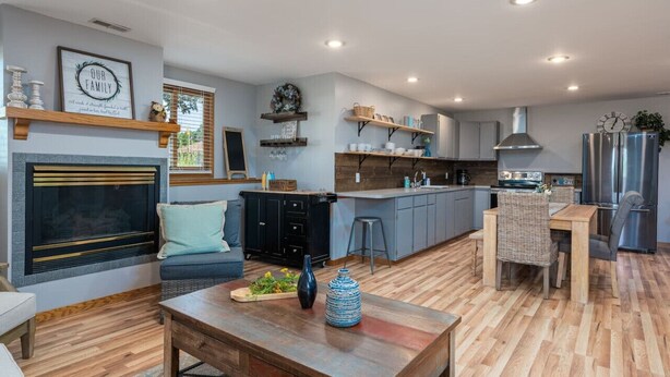 A modern kitchen with a central island, built-in appliances, and a dining area with a wooden table and chairs. - Downstairs Half of Home 3 bedrooms 1.5 bath 6 beds (Hudsonville)