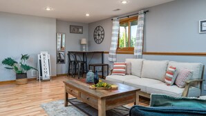 A living room with a sofa, coffee table, and a dining area with chairs and a table. - Downstairs Half of Home 3 bedrooms 1.5 bath 6 beds (Hudsonville)