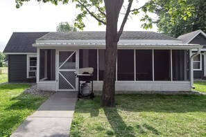 A single-story house with a covered porch, a tree in front, and a concrete pathway leading to the entrance.