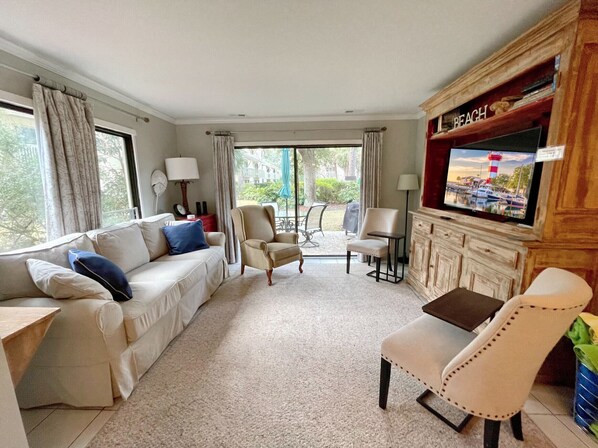 A living room with a sofa, armchairs, a TV, and a view of the outdoors.