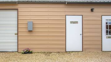 A building with a closed white garage door, a beige exterior, and a sign indicating a game cleaning room.