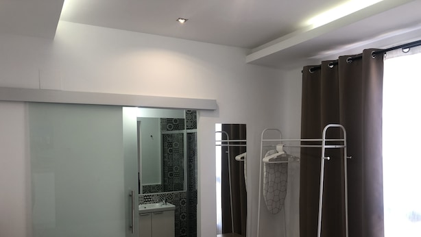 Una habitación de hotel con cama, baño con ducha y espejo.
