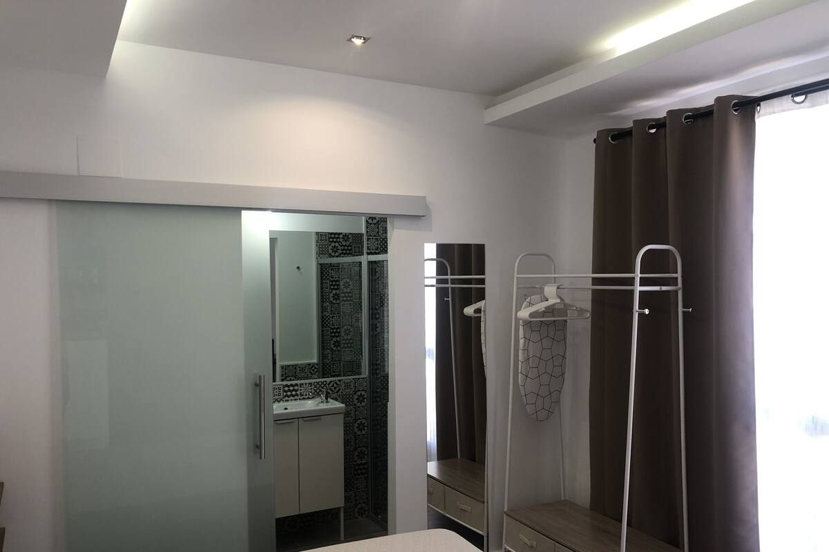 Una habitación de hotel con cama, baño con ducha y espejo.