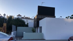 Un edificio moderno con techo plano, un gran cartel negro y una entrada con reja.