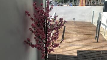 Une terrasse en bois avec un cerisier en pot.