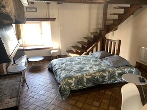 Et soveværelse med seng, et lille bord, en stol, en trappe og et vindue.