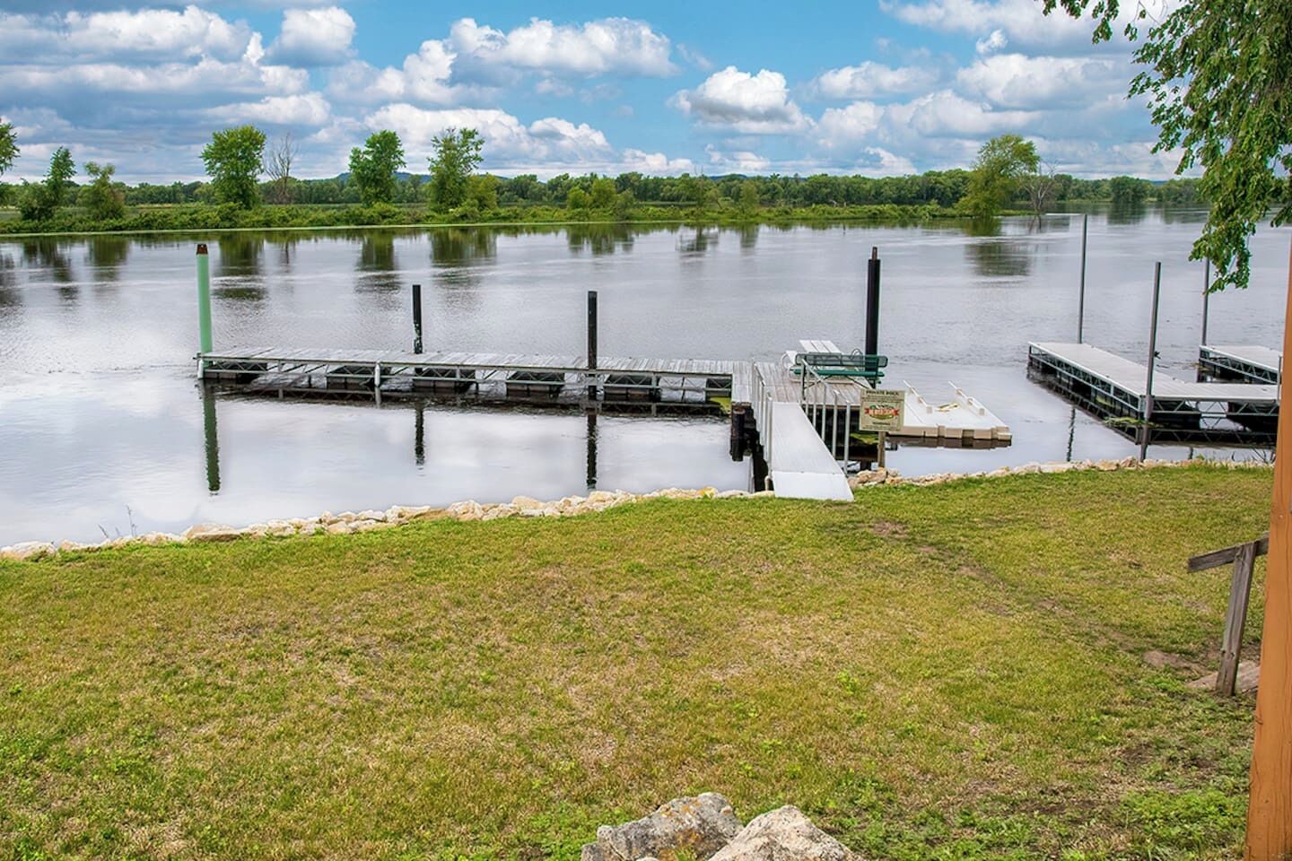 A calm lake with docks, grassy banks, and a clear sky.
