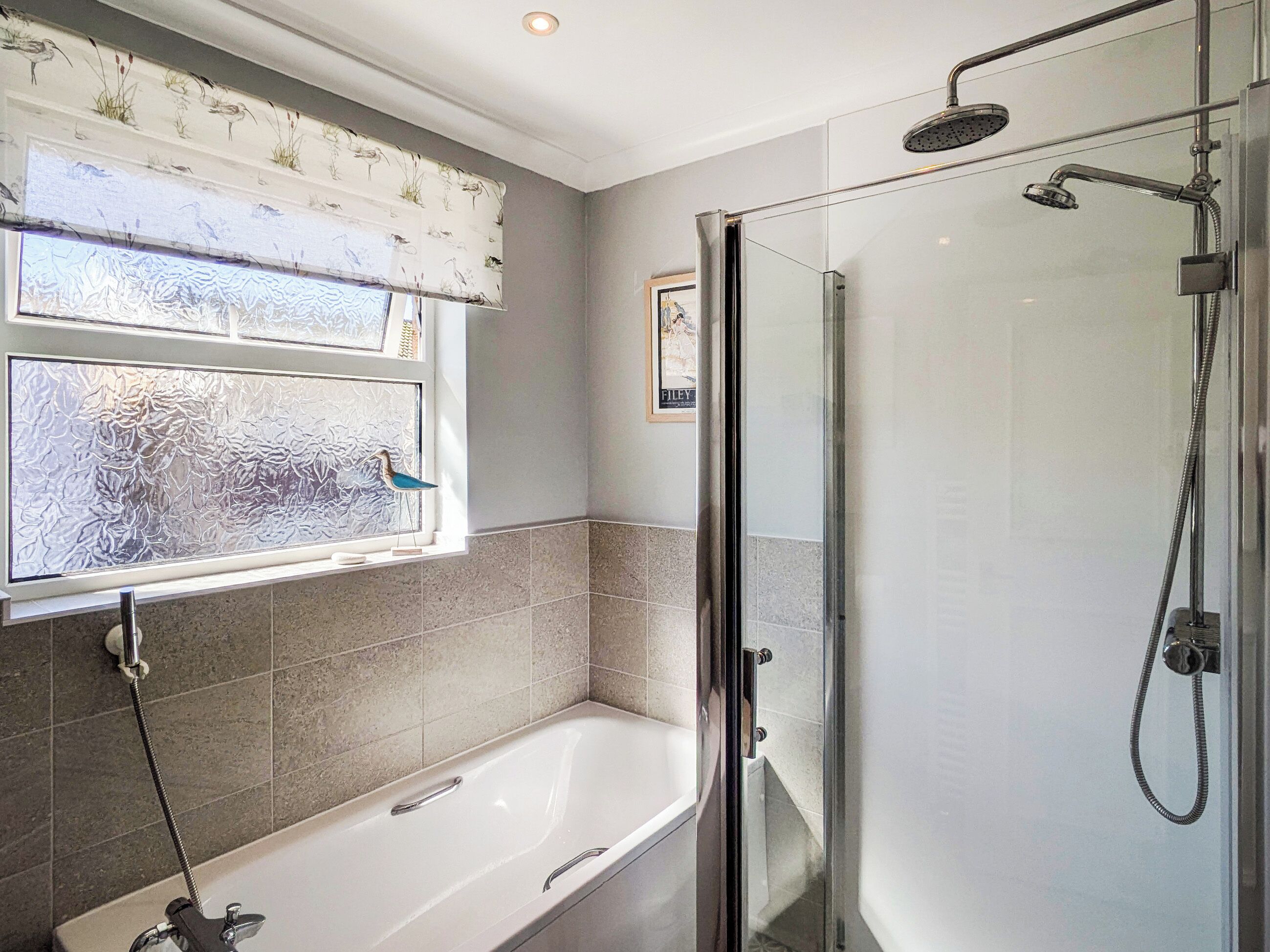 A bathroom with a bathtub, a shower, and frosted glass windows.