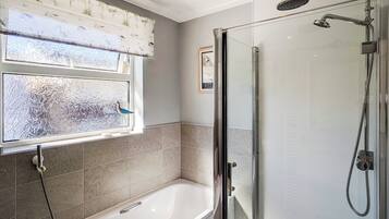 A bathroom with a bathtub, a shower, and frosted glass windows.