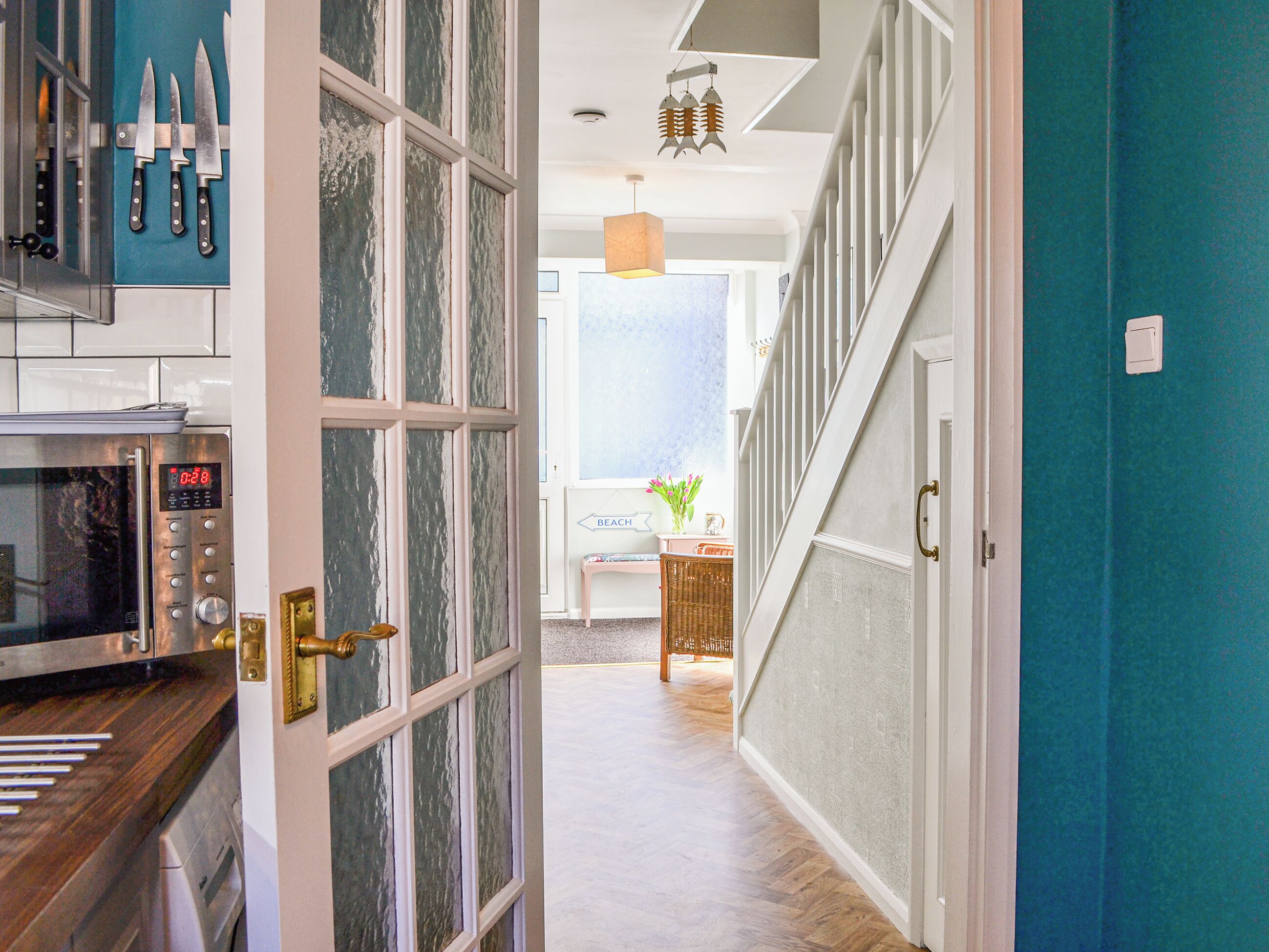 A kitchen with a microwave, a clock, and knives on the wall.