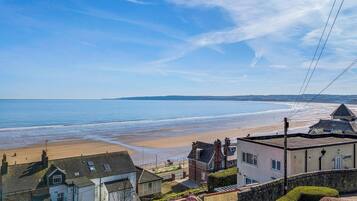 A coastal view with a sandy beach, houses, and a clear sky.
