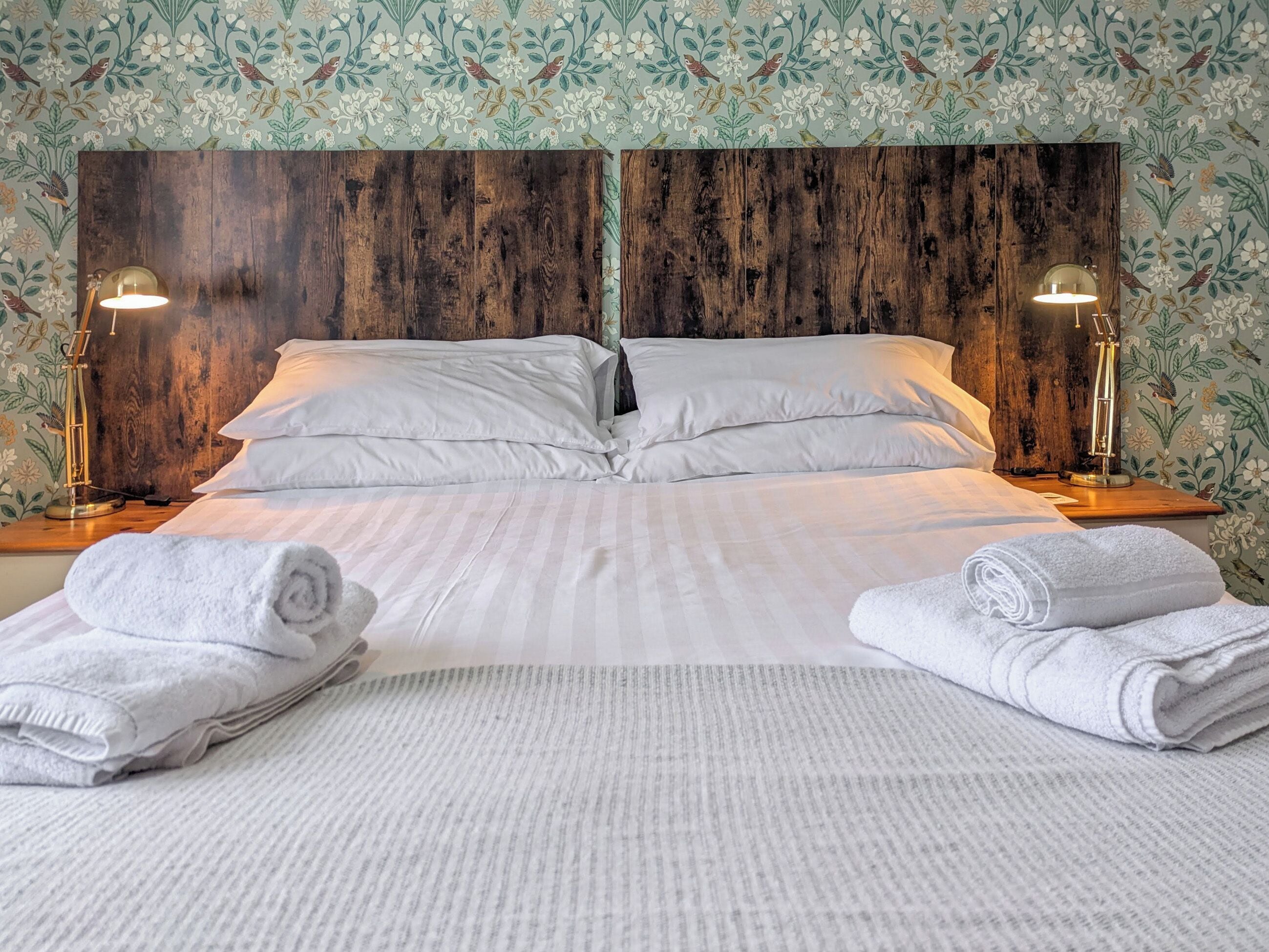 A neatly made bed with white linens and two lamps on either side.