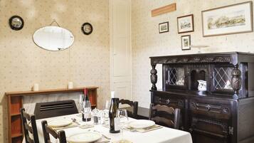 A dining room with a table set for four, a mirror, and a decorative cabinet.