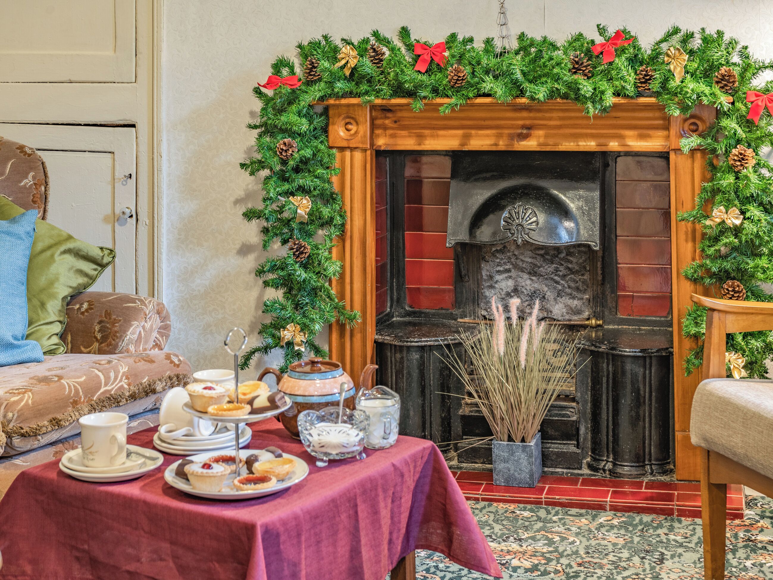 Una habitación con chimenea, una mesa con mantel rojo y un adorno navideño.