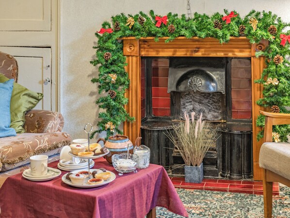 Ein Zimmer mit Kamin, einem Tisch mit roter Tischdecke und einem Weihnachtskranz.