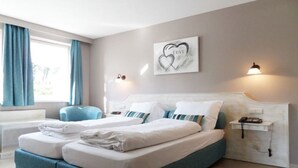 Ein Doppelbett mit weißer Bettwäsche, ein Telefon am Kopfteil und eine Wandleuchte.