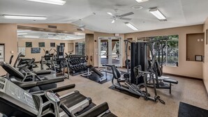 Uma academia com esteiras, aparelhos de musculação e um espelho grande.